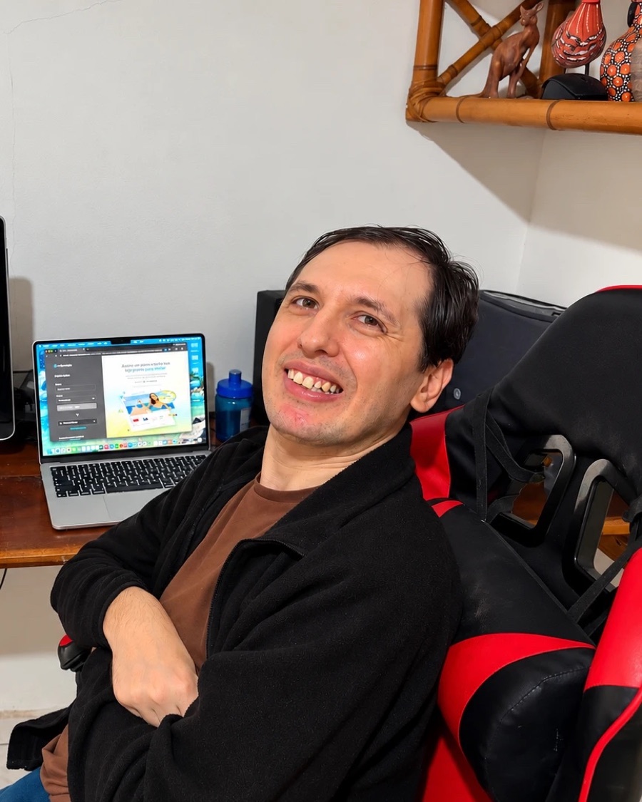Bruno sorrindo em sua mesa de trabalho, ao lado de um MacBook aberto em uma loja virtual